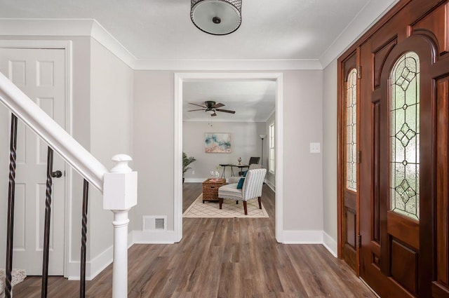 foyer entrance featuring stairs, a wealth of natural light, ornamental molding, and visible vents