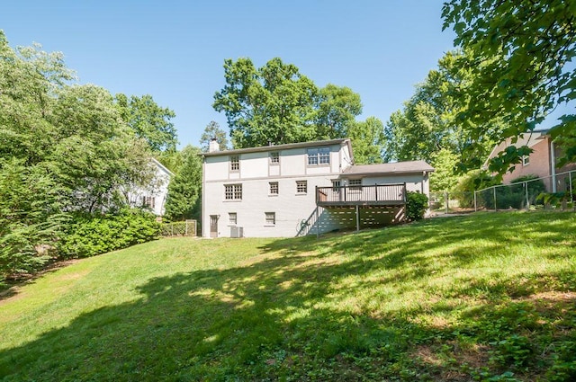 back of property featuring a chimney, fence, a deck, and a yard