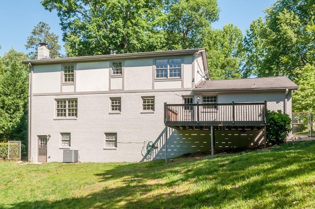 back of property featuring brick siding, a yard, a chimney, cooling unit, and a wooden deck