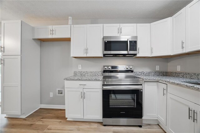 46 Forkwood Cir, Hiram, GA 30141 - kitchen featuring light stone countertops, light wood-type flooring, a textured ceiling, white cabinets, and appliances with stainless steel finishes