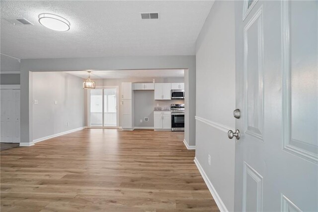 46 Forkwood Cir, Hiram, GA 30141 - unfurnished living room with a textured ceiling, visible vents, light wood-style flooring, and baseboards