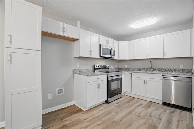 46 Forkwood Cir, Hiram, GA 30141 - kitchen featuring a textured ceiling, white cabinets, light wood-style flooring, and stainless steel appliances