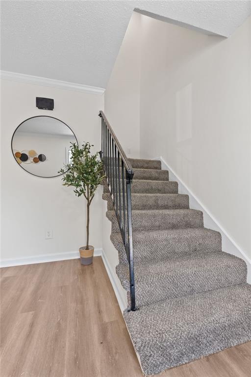 4701 Flat Shoals Rd Unit 56E, Union City, GA 30291 - stairs featuring hardwood / wood-style flooring, ornamental molding, and a textured ceiling