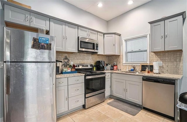 kitchen featuring appliances with stainless steel finishes, tasteful backsplash, gray cabinetry, and sink