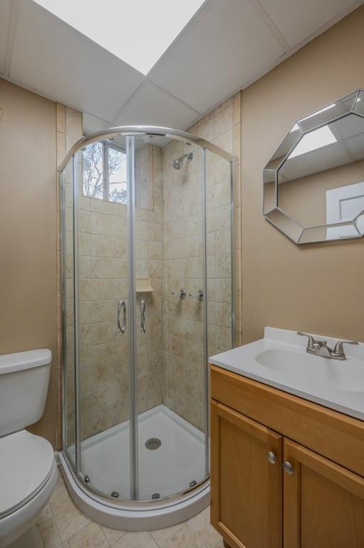 bathroom featuring tile patterned floors, vanity, toilet, and walk in shower