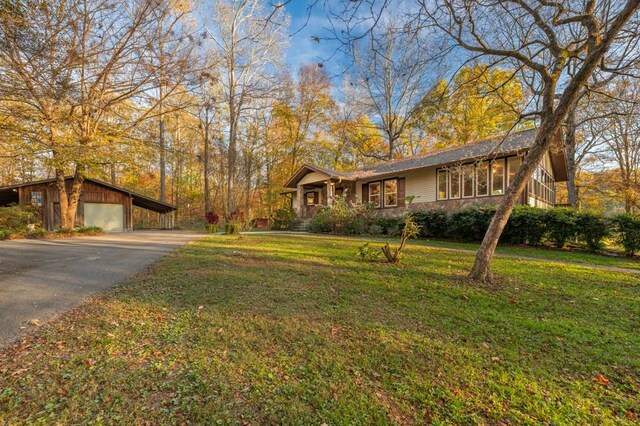 view of front of house featuring a carport, a garage, an outdoor structure, and a front lawn