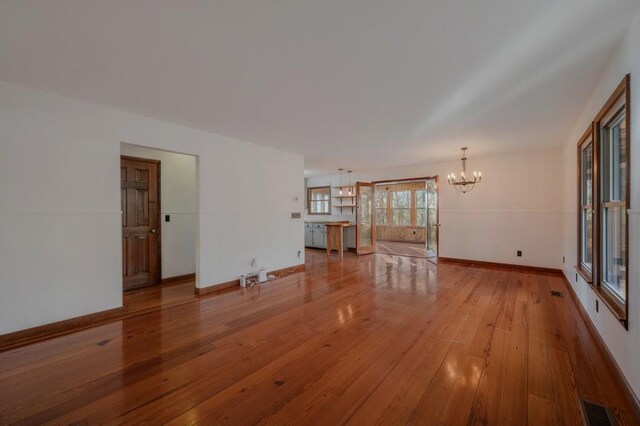 unfurnished living room featuring a notable chandelier and light hardwood / wood-style floors