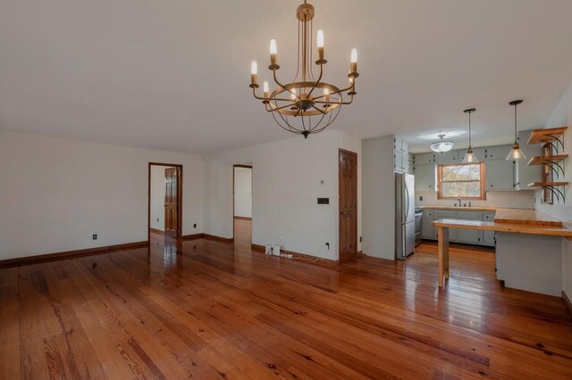kitchen with hardwood / wood-style floors, an inviting chandelier, wooden counters, hanging light fixtures, and stainless steel refrigerator