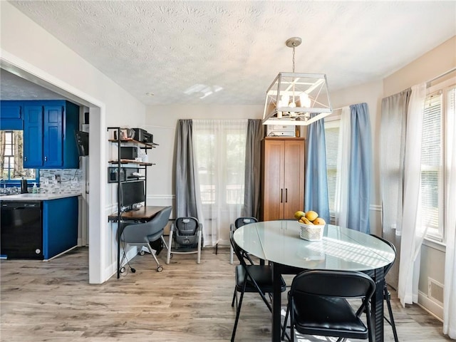 443 Rhett Dr, Loganville, GA 30052 - dining area with a chandelier, light wood-type flooring, and a textured ceiling