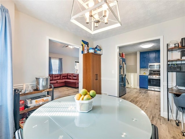 443 Rhett Dr, Loganville, GA 30052 - dining area with light wood-style floors, a textured ceiling, and a chandelier