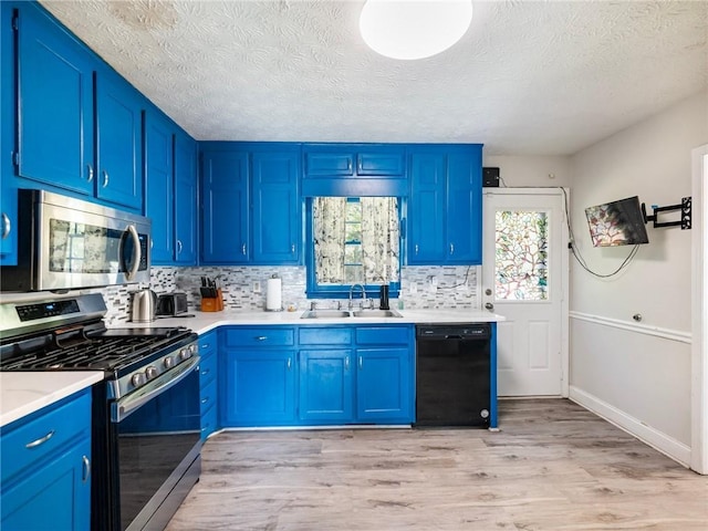 443 Rhett Dr, Loganville, GA 30052 - kitchen with stainless steel appliances, blue cabinetry, light wood-type flooring, decorative backsplash, and a textured ceiling