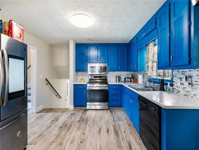 443 Rhett Dr, Loganville, GA 30052 - kitchen featuring stainless steel appliances, blue cabinetry, light wood-style flooring, and a textured ceiling