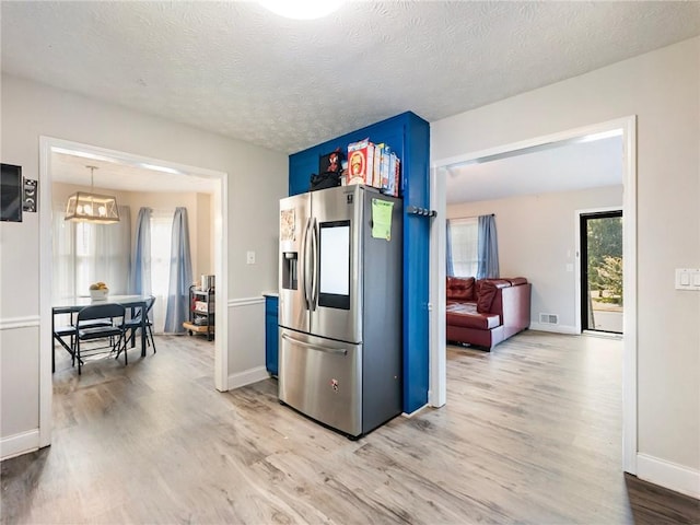 443 Rhett Dr, Loganville, GA 30052 - kitchen featuring stainless steel fridge, light wood finished floors, blue cabinetry, and a textured ceiling