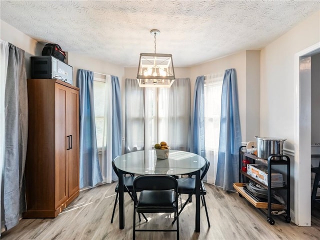 443 Rhett Dr, Loganville, GA 30052 - dining area with a chandelier, light wood-style floors, and a textured ceiling