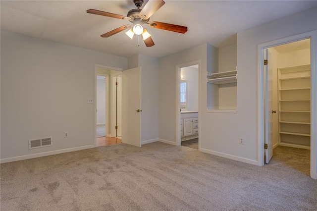 unfurnished bedroom with light carpet, a walk in closet, ceiling fan, connected bathroom, and a closet