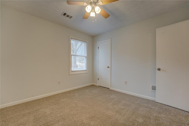 carpeted empty room featuring ceiling fan and a textured ceiling