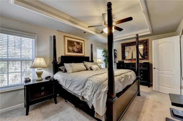 carpeted bedroom with a tray ceiling, ceiling fan, and crown molding