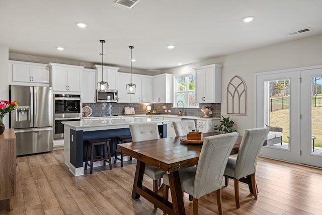 dining room with a wealth of natural light, sink, and light hardwood / wood-style flooring