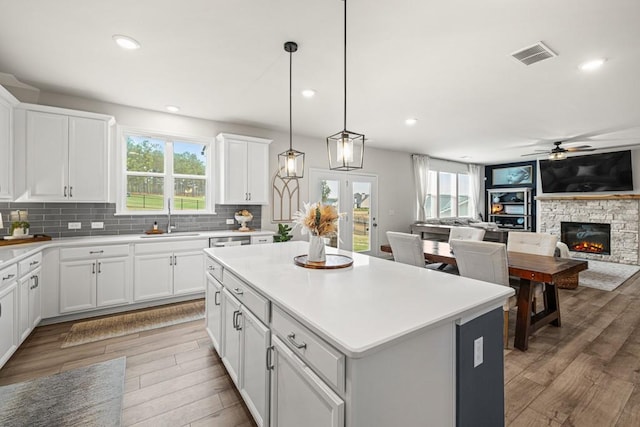 kitchen with white cabinets, light wood-type flooring, a fireplace, and a kitchen island