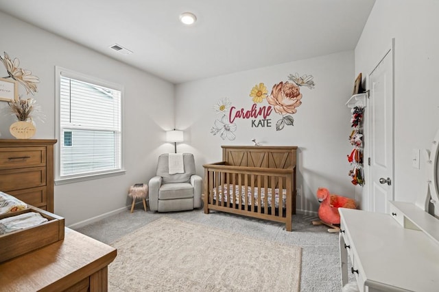 carpeted bedroom featuring a nursery area