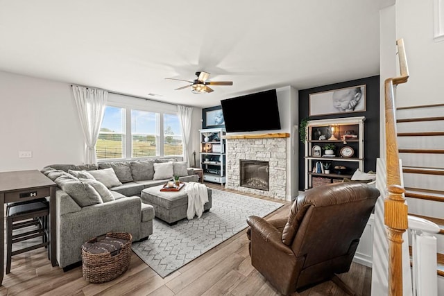 living room with a fireplace, light hardwood / wood-style flooring, and ceiling fan