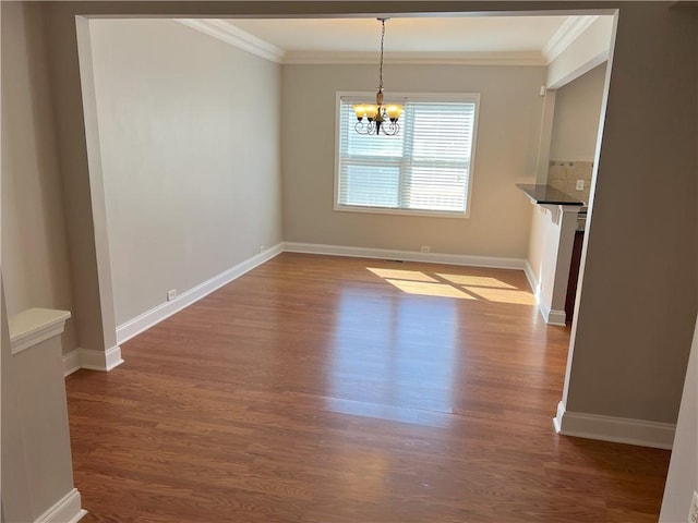 unfurnished dining area with crown molding, wood-type flooring, and a chandelier