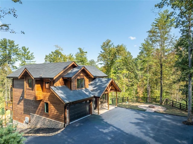 view of front facade featuring driveway, an attached garage, and fence