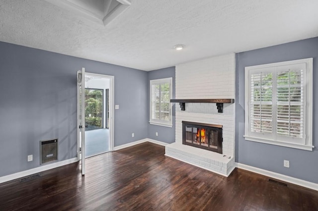 881 Mclinden Ave SE, Smyrna, GA 30080 - unfurnished living room featuring wood finished floors, a fireplace, a textured ceiling, and heating unit