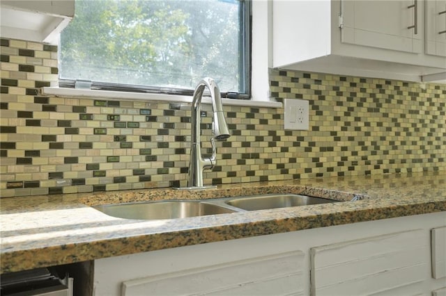 room details with backsplash, sink, and white cabinets