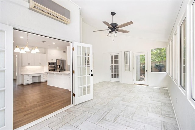 unfurnished sunroom with french doors, a wall unit AC, and lofted ceiling