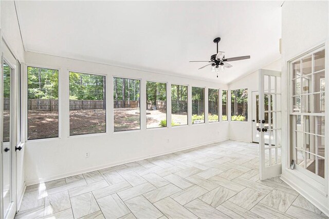 unfurnished sunroom featuring baseboards, lofted ceiling, and french doors