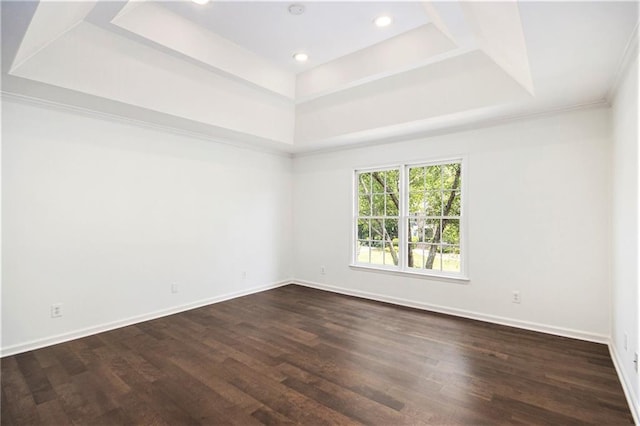 spare room with a raised ceiling, dark wood-type flooring, baseboards, and recessed lighting