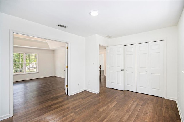 unfurnished bedroom with dark wood finished floors, baseboards, and a closet