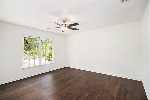 unfurnished room with dark wood finished floors, a ceiling fan, and baseboards