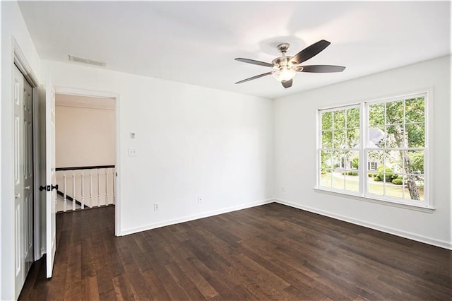 empty room featuring a ceiling fan, dark wood-style flooring, and baseboards