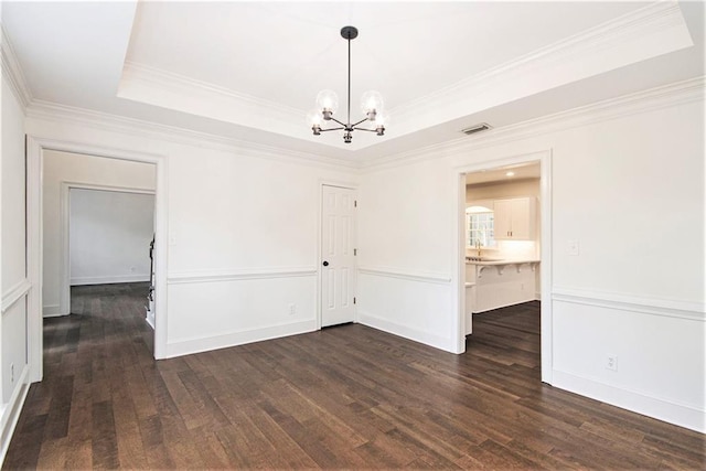 spare room with a chandelier, wood finished floors, a raised ceiling, and crown molding