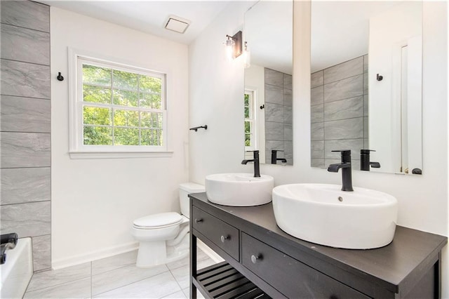 full bath with toilet, double vanity, a bath, and baseboards