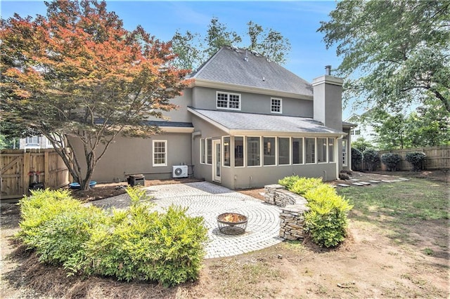 rear view of property featuring an outdoor fire pit, a sunroom, a patio area, a fenced backyard, and a shingled roof