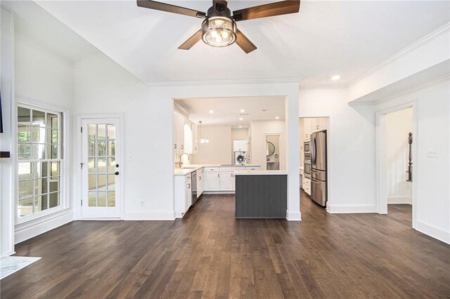 unfurnished living room with dark wood-style flooring, a sink, ceiling fan, baseboards, and ornamental molding