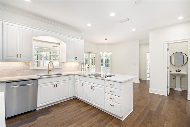 kitchen featuring stainless steel dishwasher, a sink, a peninsula, decorative backsplash, and a chandelier