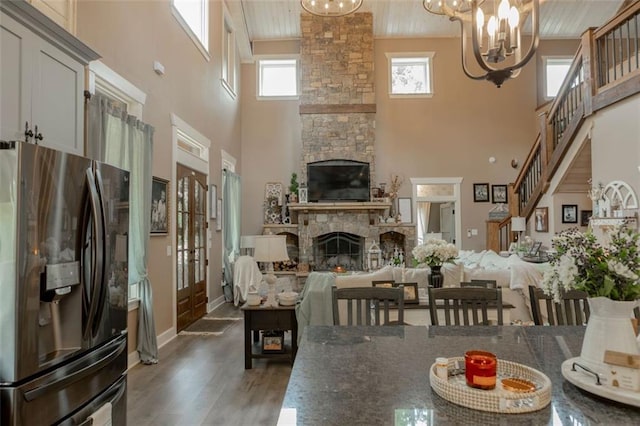 dining area with a wealth of natural light, a high ceiling, a stone fireplace, and dark hardwood / wood-style flooring