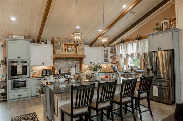 kitchen featuring a kitchen island, a breakfast bar area, beamed ceiling, appliances with stainless steel finishes, and light hardwood / wood-style floors