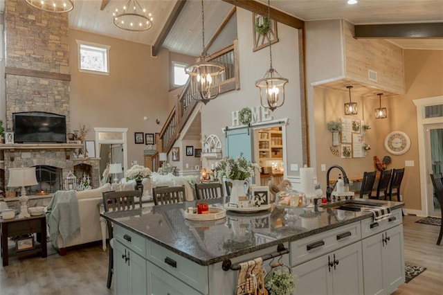 kitchen with a center island with sink, a barn door, pendant lighting, and high vaulted ceiling