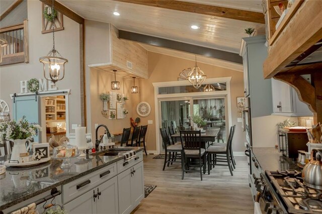 kitchen with white cabinets, a barn door, sink, and pendant lighting