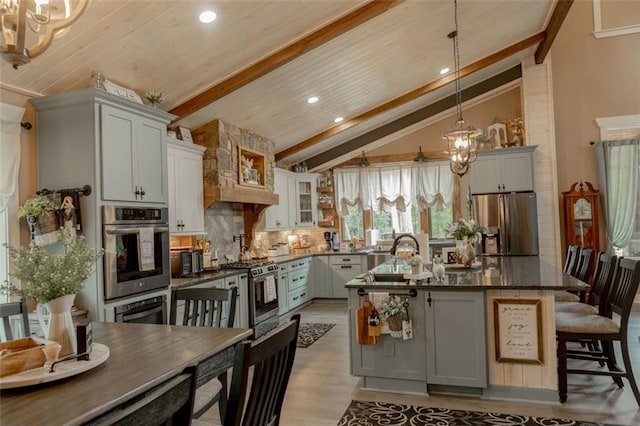 kitchen featuring hanging light fixtures, stainless steel appliances, a breakfast bar, lofted ceiling with beams, and a center island