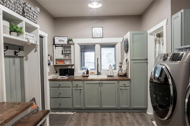 laundry area featuring sink, independent washer and dryer, light hardwood / wood-style floors, and cabinets