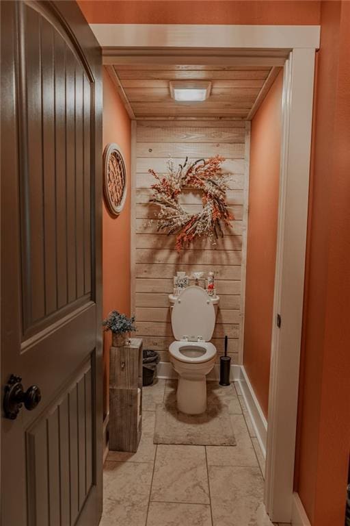 bathroom featuring toilet, wood walls, and wood ceiling