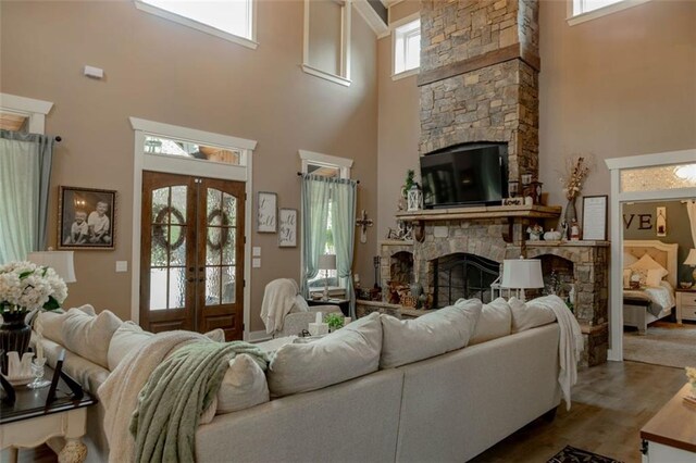 living room featuring a towering ceiling, french doors, and a healthy amount of sunlight