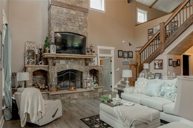 living room with a stone fireplace, hardwood / wood-style flooring, and high vaulted ceiling