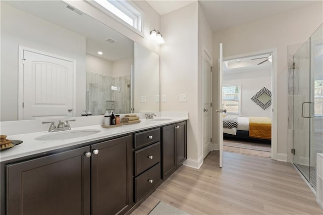 ensuite bathroom featuring visible vents, a sink, a shower stall, and wood finished floors